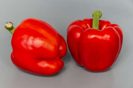 Two ripe and beautiful red peppers on a gray background. close-up. Bulgarian pepper.の写真素材