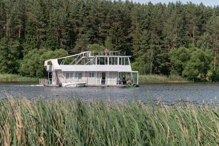 Minsk. Belarus. 08.15.2022. A ship in the form of a two-story houseboat floats along the river. Cruise on the river. summer outdoor recreation.の写真素材