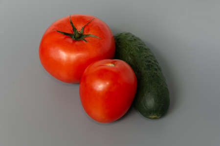 Ripe and beautiful tomatoes and cucumber on a gray background. close-up. Vegetarian food.の写真素材