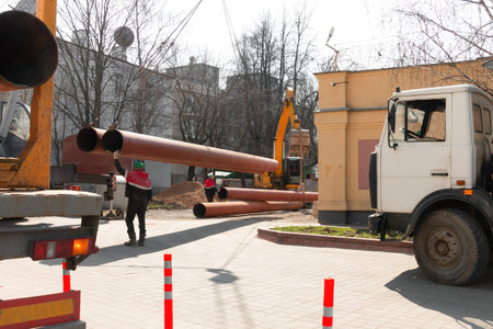 Laying heating pipes with a crane. construction work in the city. Installation of underground water...