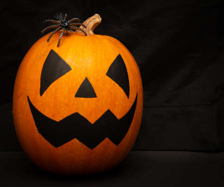 Halloween pumpkin with candles, spider sits on top, close-upの写真素材