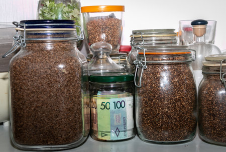 Belarusian paper money in a glass jar among other jars with cereals and dried fruits. Keeping money in a glass jar. Secret piggy bank. Money saving concept. Keeping cash at home. financial reserves.の写真素材