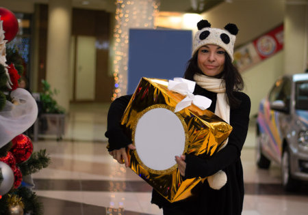 Girl with a big box of Christmas gifts in the mall. Buying gifts for Christmas.の写真素材