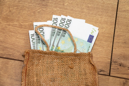 Bag with 100 Euro banknotes in a jute bag. economics and finance. Cash wages in cash. wooden background. close-up.の写真素材