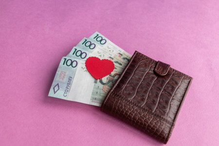 Brown leather wallet with red heart. Belarusian hundred-ruble bills stick out of the wallet. close-up. The concept of cash costs for the purchase of gifts for Valentine's Day, wedding, birthday.の写真素材