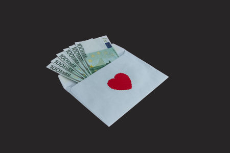 Paper envelope with 100 euro banknotes and a red heart on a black background. Banknotes stick out...