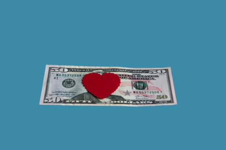 Red heart on a fifty dollar bill isolated on a blue background. Conceptual gift for Valentine's Day, wedding, birthday. close-up.の写真素材