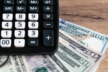 Dollars, leather brown wallet and calculator on a wooden background. business and finance concept....