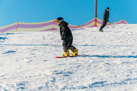 logoisk. Belarus. 10/01/2023. A teenage snowboarder descends the slope of a snow-covered mountain in special equipment. Winter sports concept. Snowboard - descent at high speed on prepared slopes.の写真素材