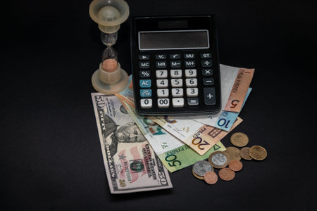 Banknotes and coins of the Republic of Belarus, fifty US dollars, an hourglass and a calculator on a...