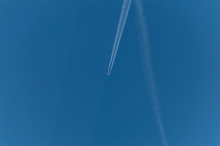 The plane flies through the clear blue sky leaving long trails of steam. With copy space to add text.の写真素材