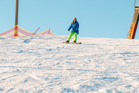 logoisk. Belarus. 07/01/2023. A snowboarder girl descends from the slope of a snow-covered mountain in special equipment. Ski resort in Belarus. Winter extreme sport. winter holidays.のeditorial素材