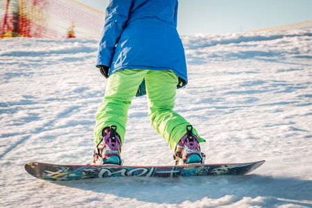 logoisk. Belarus. 05/01/2023. A snowboarder girl descends from the slope of a snow-covered mountain in special equipment. Winter extreme sport. Ski resort in Belarus. winter holidays.のeditorial素材