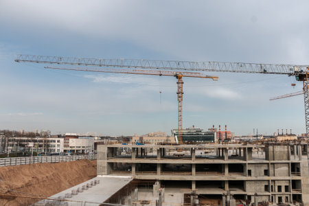 Construction cranes at a construction site in the city against the blue sky. The concept of building a new area. Construction of a new building.の写真素材