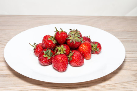 Fresh ripe strawberries with tails in a white plate. Beautiful and tasty strawberries. Dessert. close-upの写真素材
