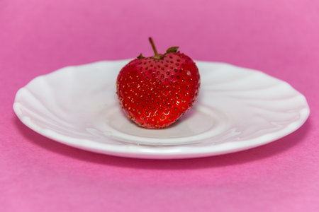 Fresh ripe strawberries in a white plate on a pink background. Beautiful and tasty strawberries. Dessert. Diet. close-up.の写真素材
