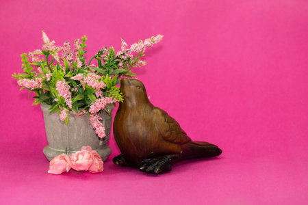 Wooden bird with pink flowers on pink backgroundの写真素材