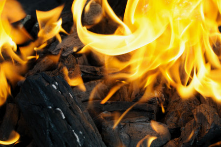 Burning charcoal with a flame in orange and yellow