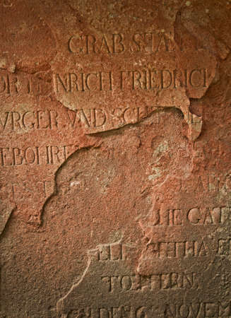 Gravestone Ancient red sand stone with latin inscription broken and weatheredの写真素材