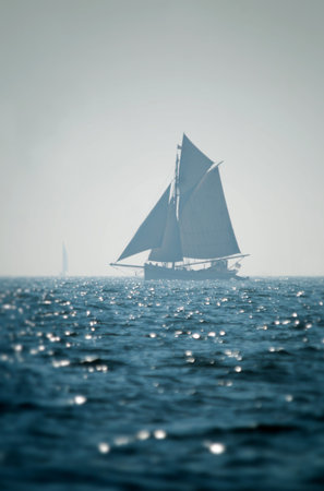 Sailing boat far away silhouette with deep blue sea in front