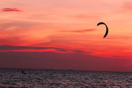 Kite-surfing on orange sunset s background at pattaya,Thailandの写真素材
