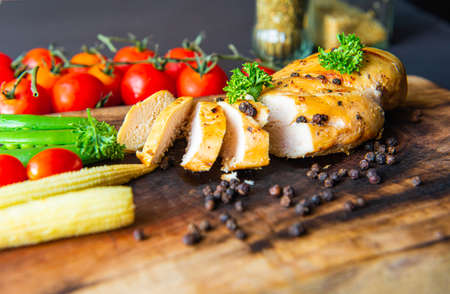 Grilled chicken breast on wood butcher background, tomatoesの写真素材