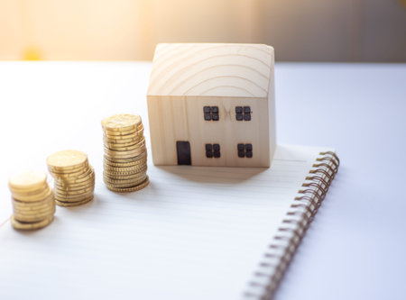 Mini wooden house with coin and notepad, on business saving and investment concept
