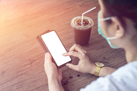 Asian woman wearing medical mask using a Smartphone's in cafe after Quarantine from COVID-19, soft focusの写真素材