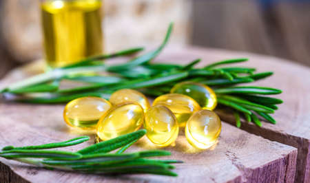 Top view Bottle glass of essential rosemary oil with rosemary on wooden rustic background. herbal oil conceptの写真素材