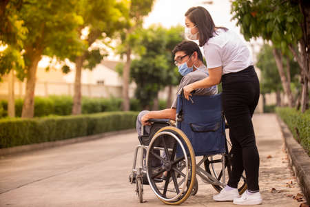 Disabled man in a wheelchair with a female nurse in the backgroundの写真素材