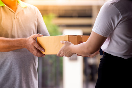 Delivery man by sending box of parcel to customers service at homeの写真素材