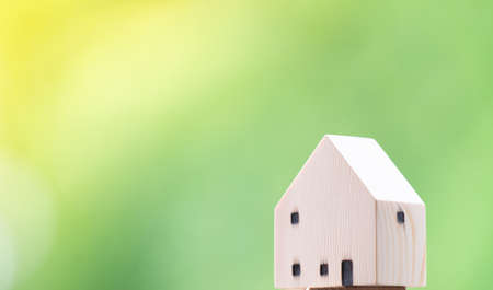 Miniature wooden house on green bokeh background with copy spaceの写真素材