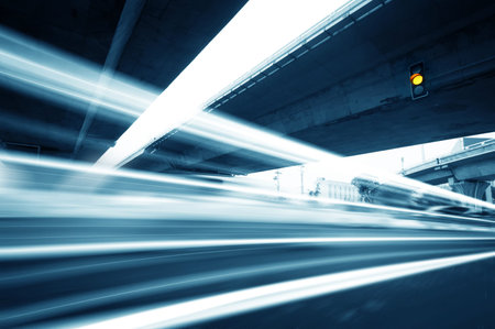 High-speed vehicles bright light trails on urban roads under the overpass at night  