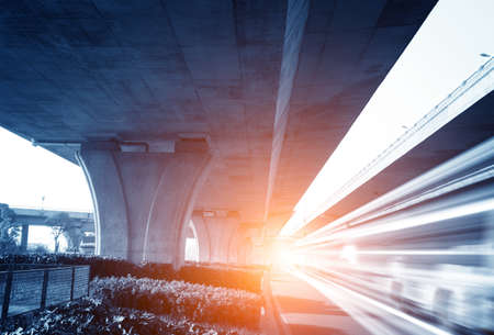 High-speed vehicles bright light trails on urban roads under the overpass at night  の写真素材