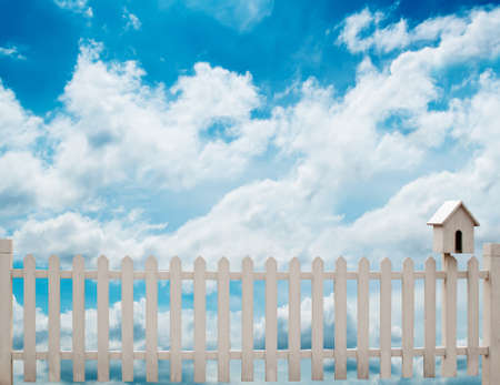 white fence with bird house and blue skyの写真素材