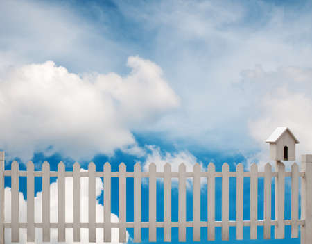 white fence with bird house and blue skyの写真素材