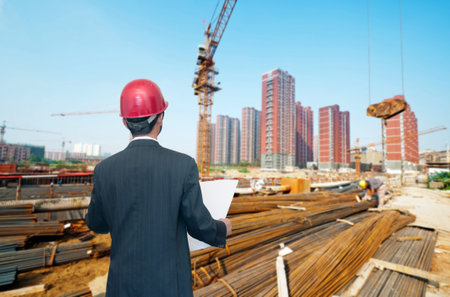 Rear view of architect looking comparing housing project with building