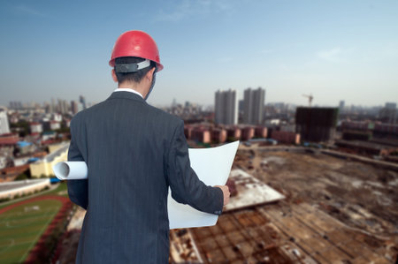 Rear view of architect looking comparing housing project with building
