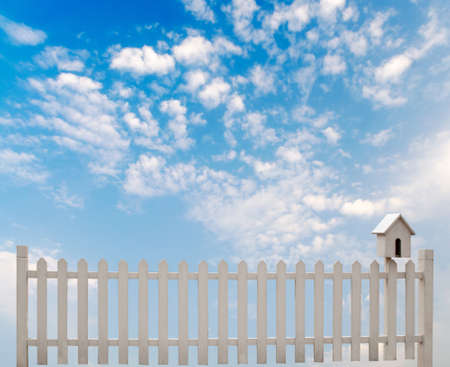 white fence with bird house and blue skyの写真素材