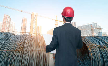 Rear view of architect looking comparing housing project with buildingの写真素材