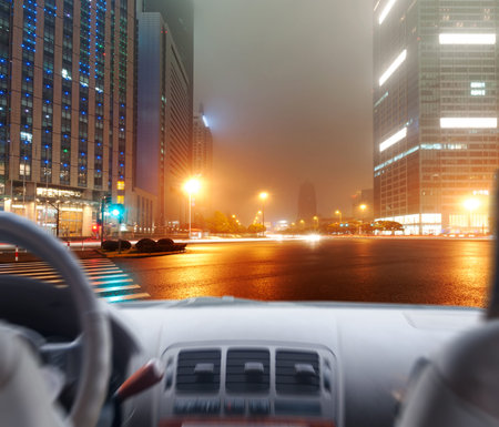 Driver's hands on a steering wheel of a car and night scene