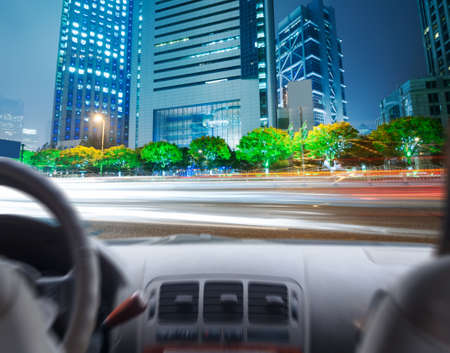 Driver's hands on a steering wheel of a car and night sceneの写真素材
