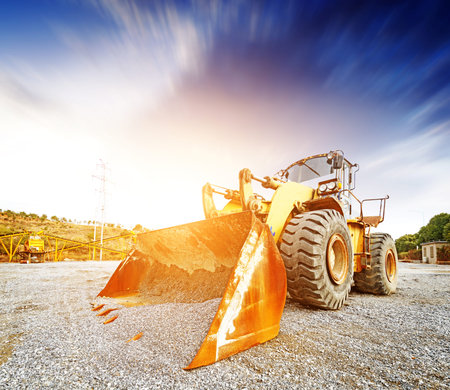 Big excavator on new construction site, in the background the blue sky and sun