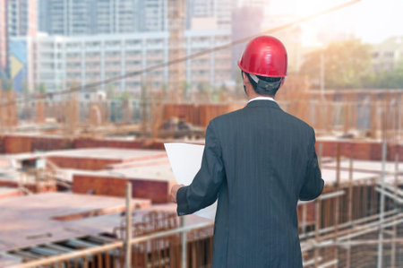 Rear view of architect looking comparing housing project with building