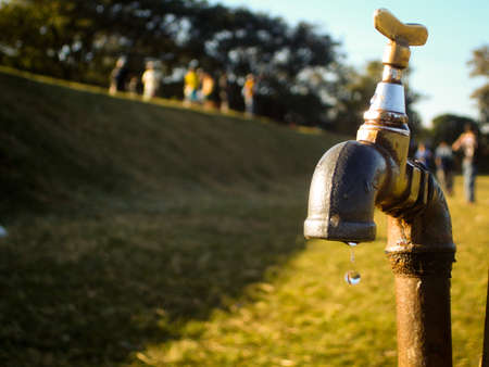 a waterdrop on a tap of a park in brazil, kids playing on the backgroundの写真素材