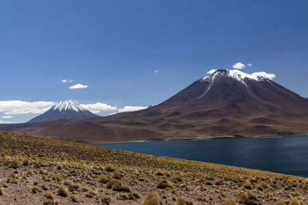 miscanti volcano with snow and its lagoon at andes mountain rangeの写真素材