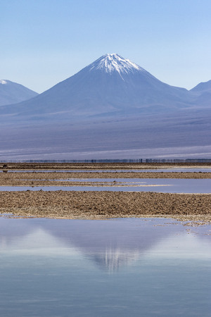 volcano reflected in salt flats lake in atacama desertの写真素材
