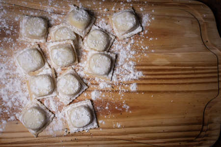 Raw ravioli in overhead view on wooden table with side negative space for writingの写真素材