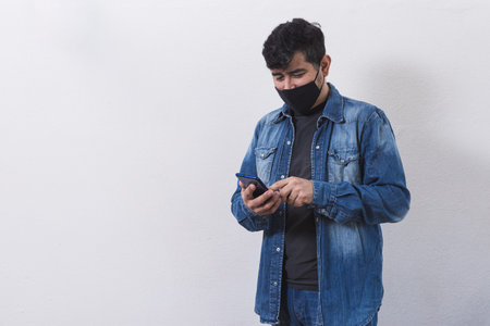 Man in jean shirt and chinstrap sending messages by mobile phoneの写真素材