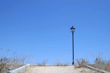 Lonely lamppost at the end of the road with blue skyの写真素材